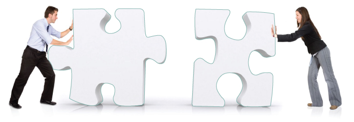 Two people pushing large jigsaw pieces toward each other until they fit.
