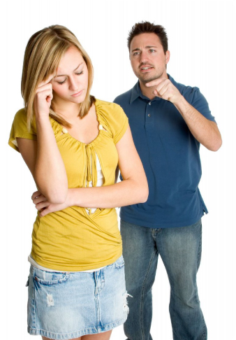 A woman looking down, arms folded, while a man beside her gestures mid-argument.